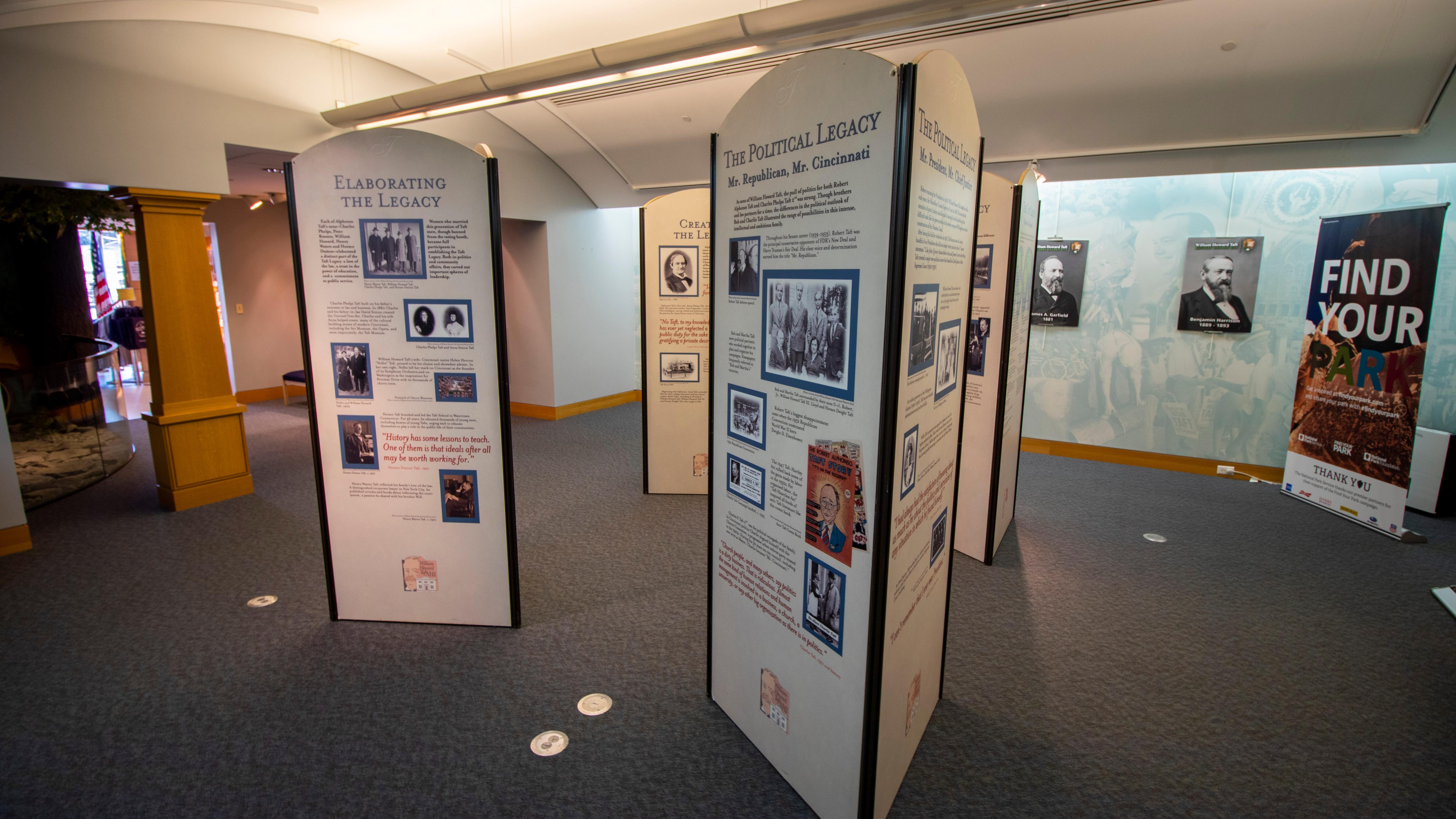 Tall display columns arranged in rows inside of a large room with photos and text on them.