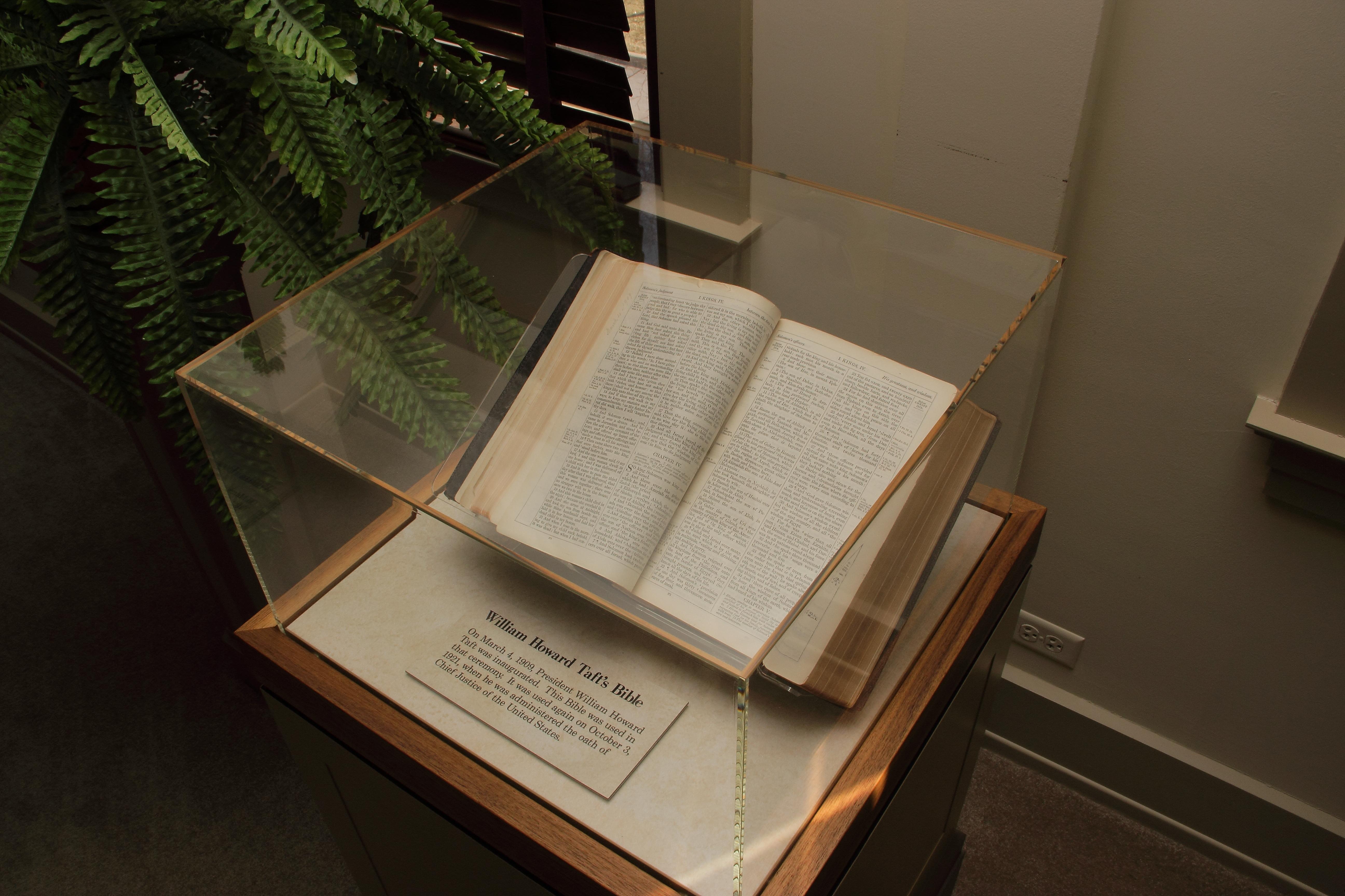 A large open book on display in a glass-enclosed case.