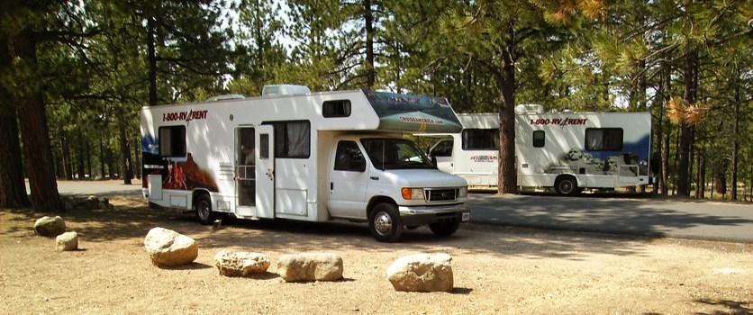 Two RVs parked at gravel campsites in Sunset Campground.