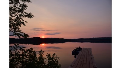 Dock at sunset overlooking Washington Harbor with a motorboat tied off to the dock.