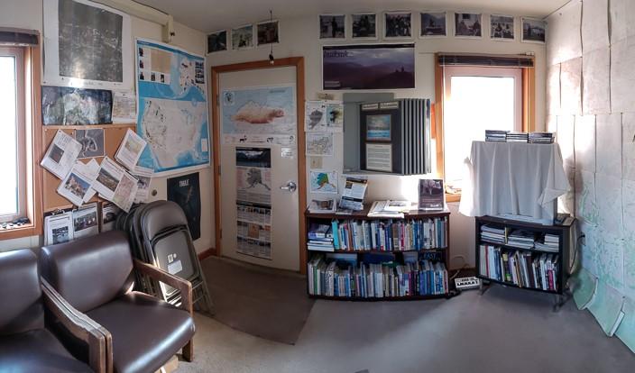 inside view of ranger station with various maps, books, and TV, along with chairs