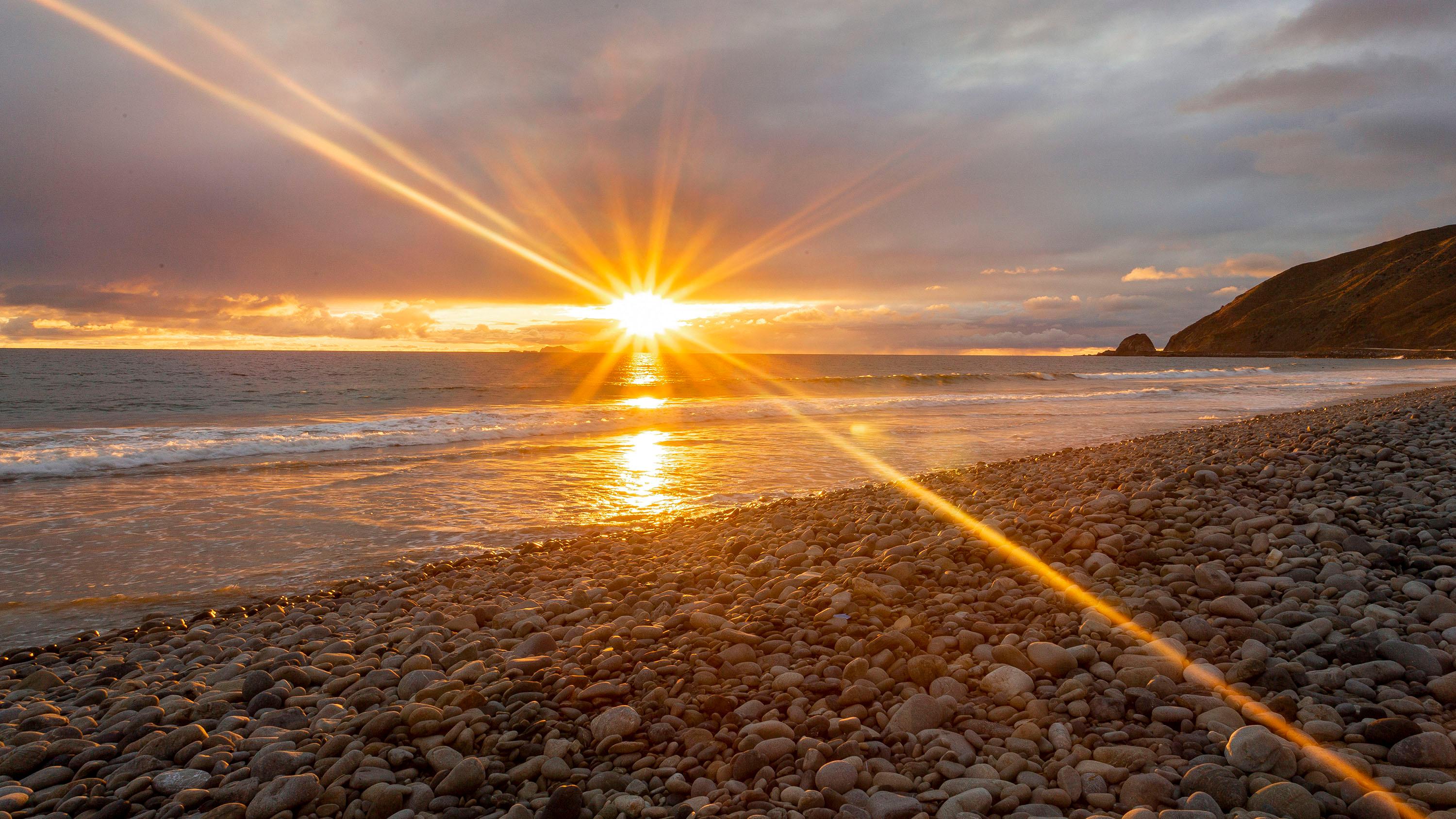 Sunbeams reaching from glowing sun over the ocean.