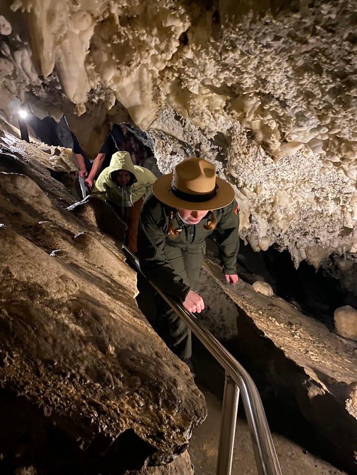 Ranger ducking and twisting to fit through a narrow cave passage.