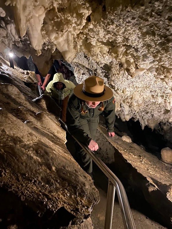 Ranger ducking and twisting to fit through a narrow cave passage.