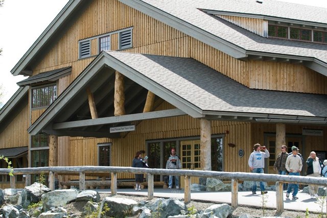 a large wood building with people milling around outside