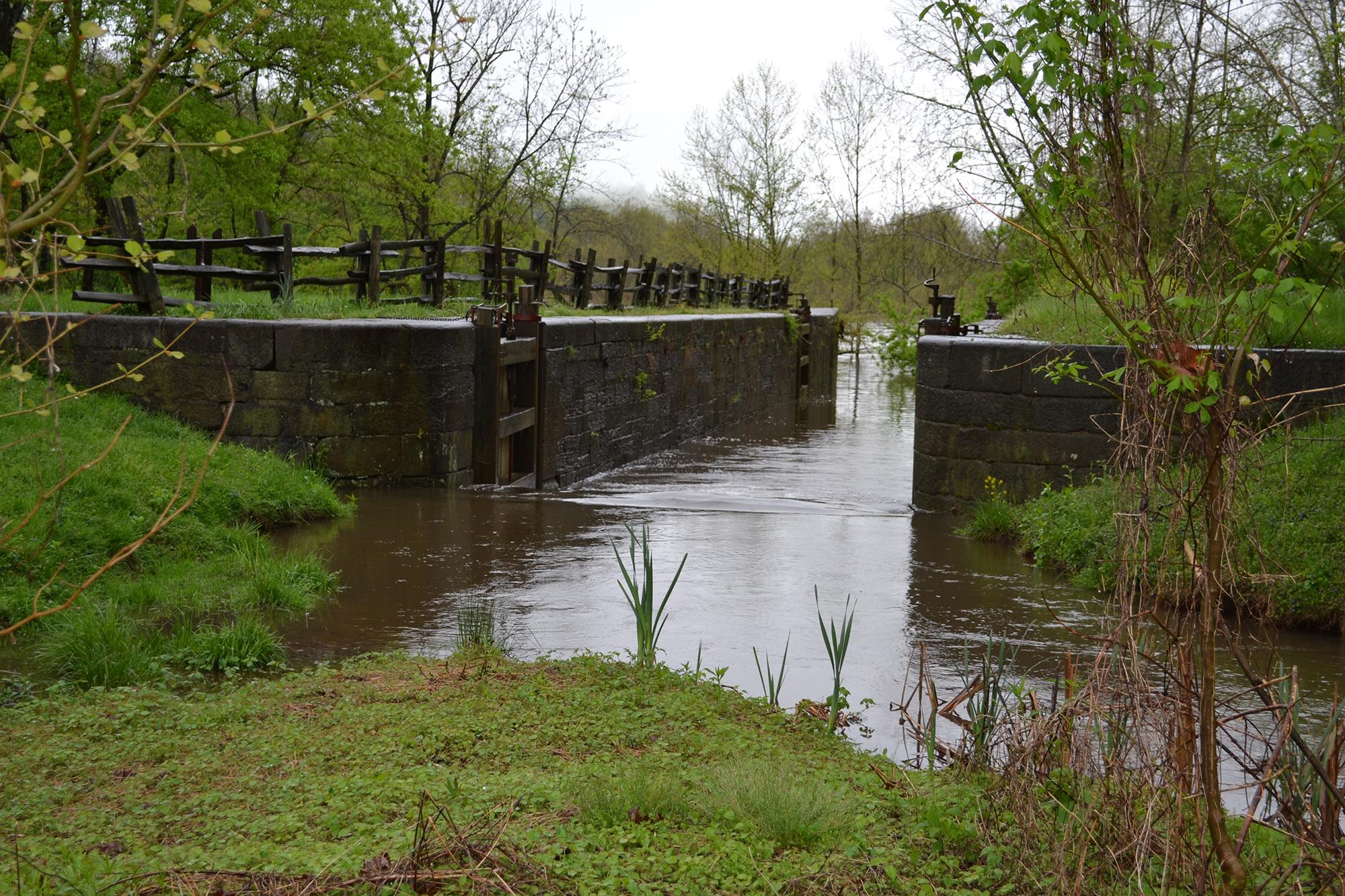 A waterway runs between 2 wood and stone walls in a canal lock
