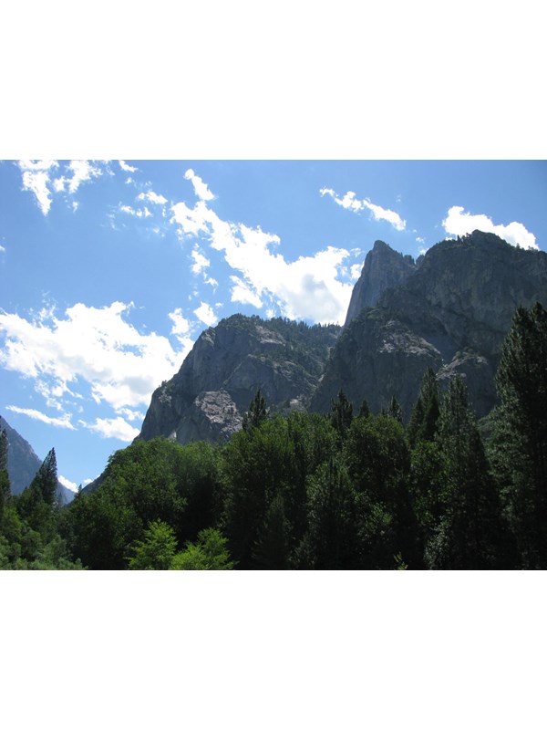 Rocky cliffs tower above a pine and cedar forest