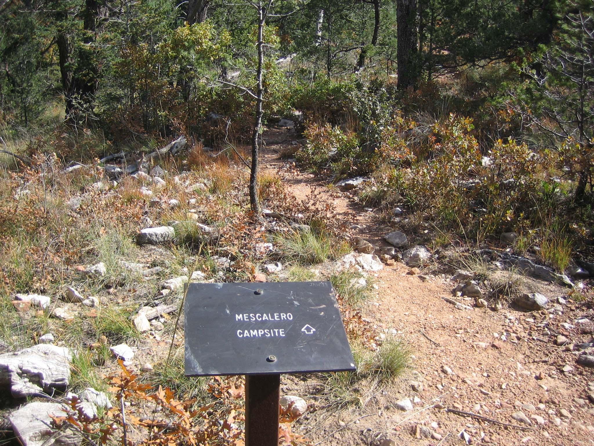 A metal sign directs hikers off the trail to the Mescalero campsites