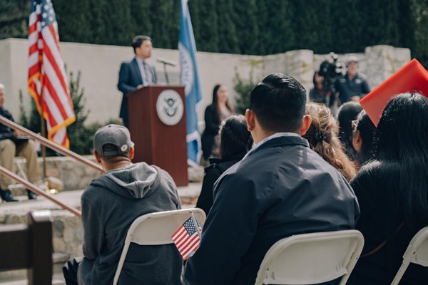 A man watches a speaker up on a podium during a Naturalization Ceremony at Cesar E. Chavez National