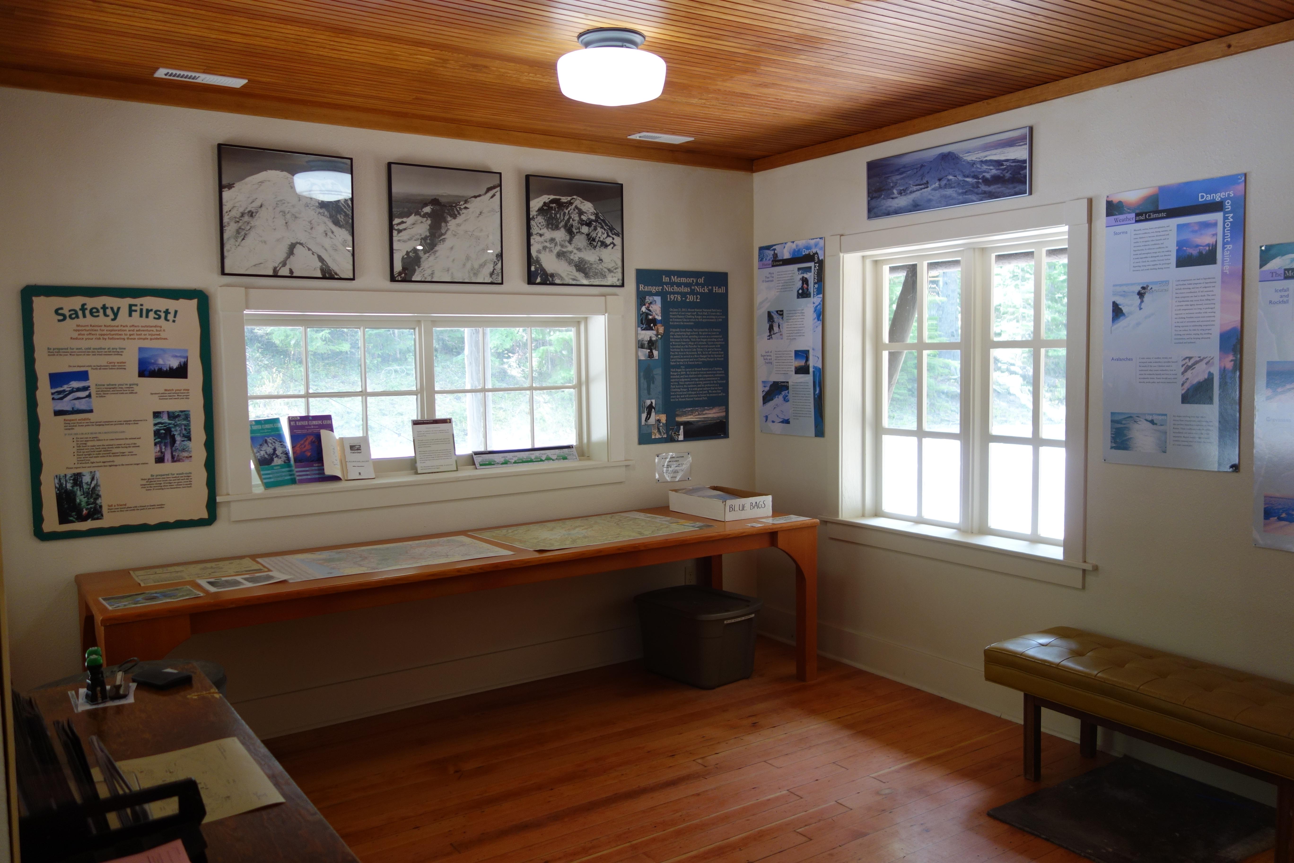 A small room with exhibit panels attached to the walls with maps and publications laid out on tables