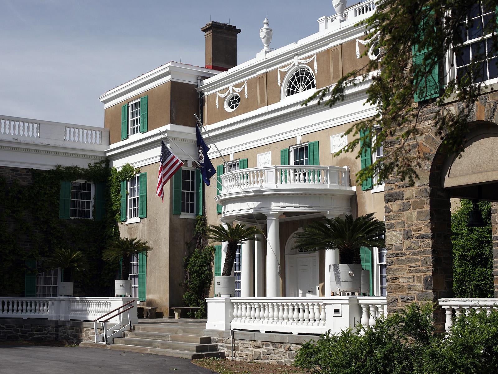 A large stucco house with white wood portico and white balustrade.