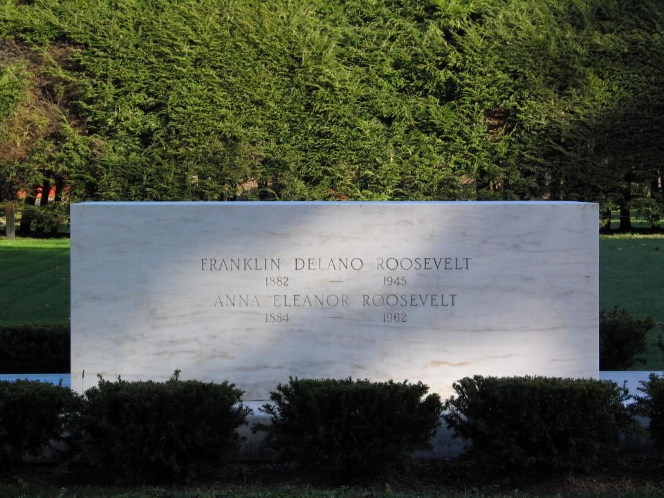 A marble stone carved with the names of Franklin D. Roosevelt and Eleanor Roosevelt on a green lawn.