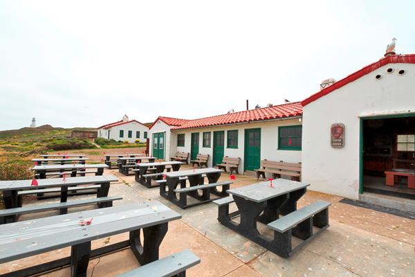 White building with red tile roof. Visitors standing in front of building.