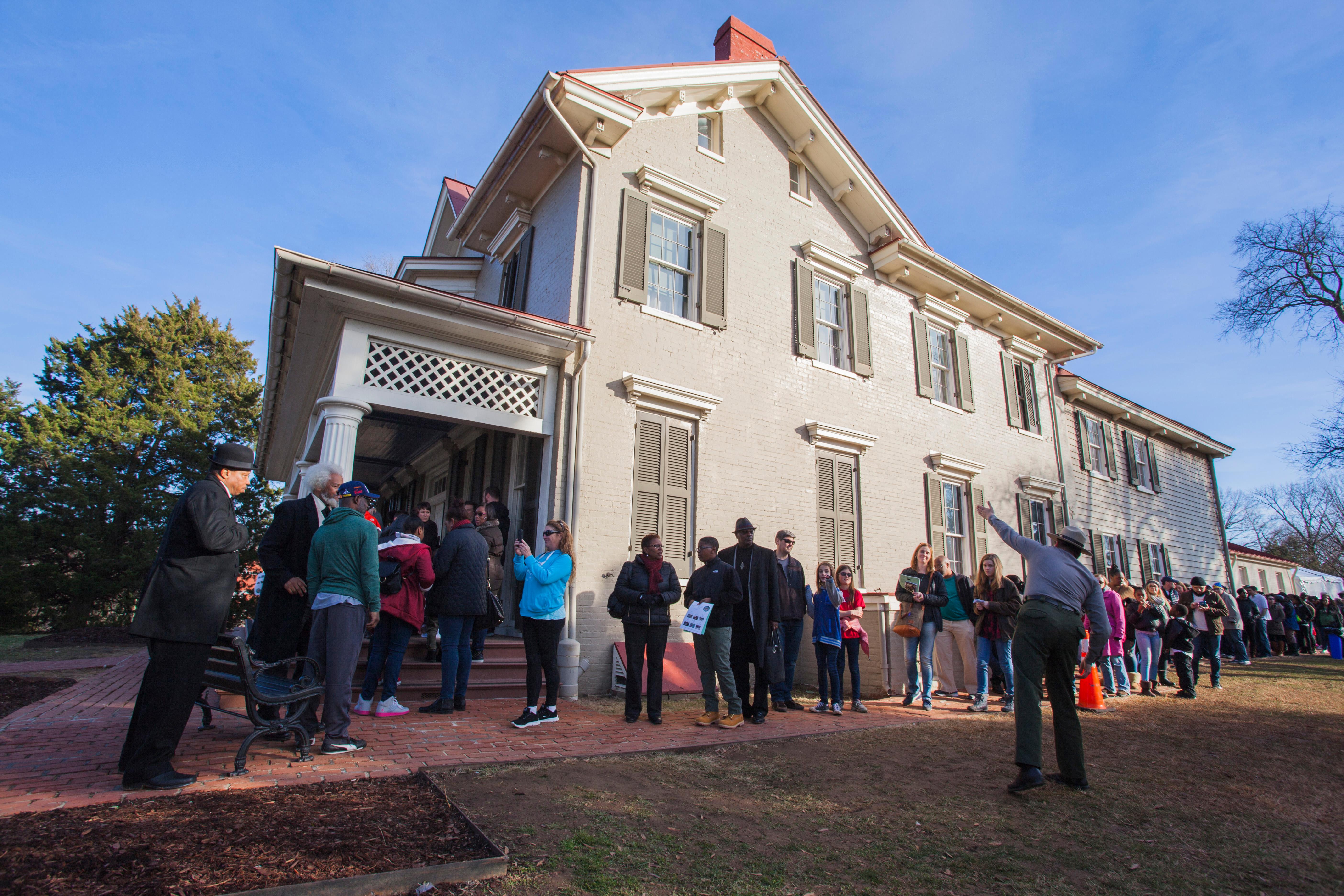 A park ranger gestures to a group of people outside the Frederick Douglass home.