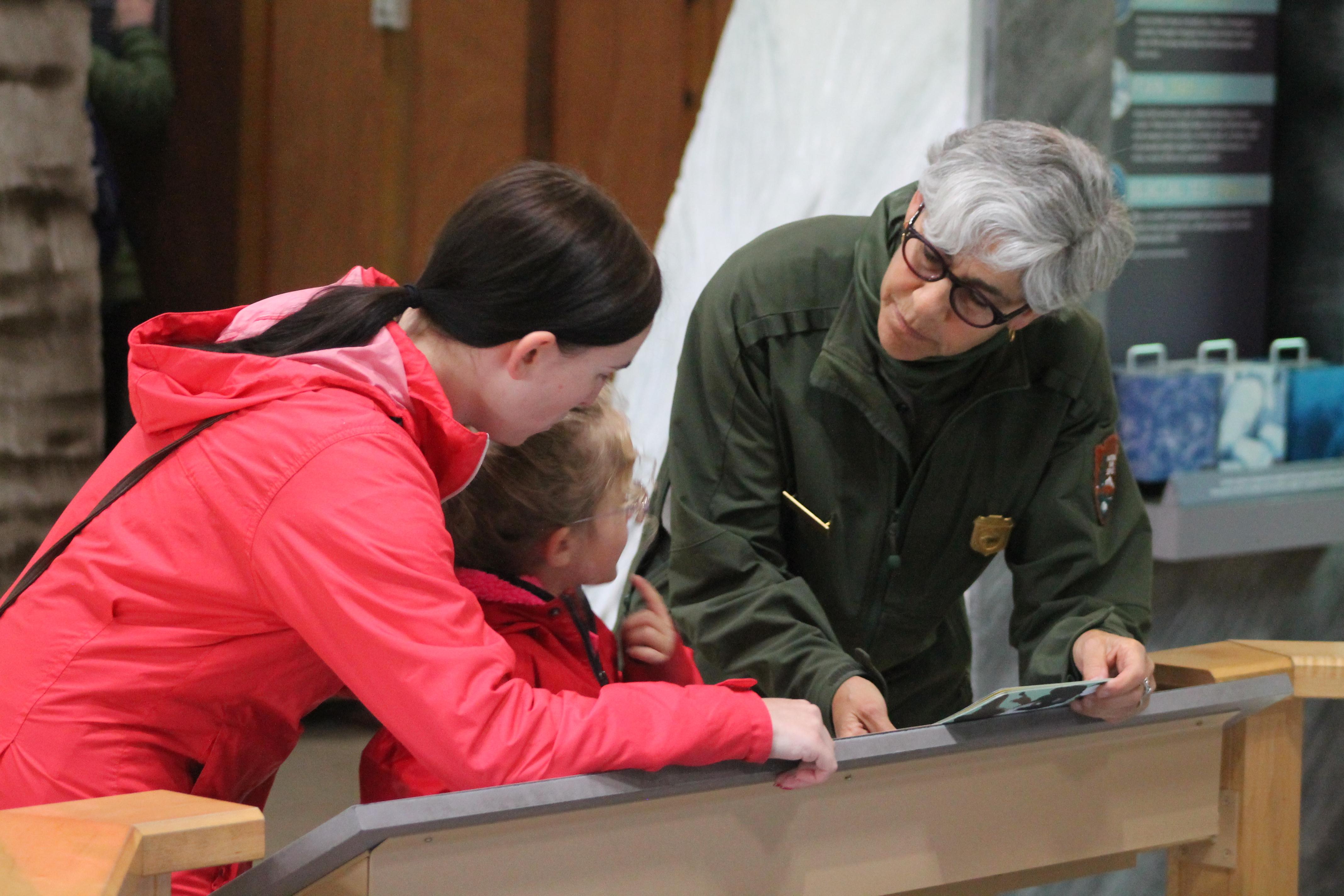 A park ranger speaks to a child and adult