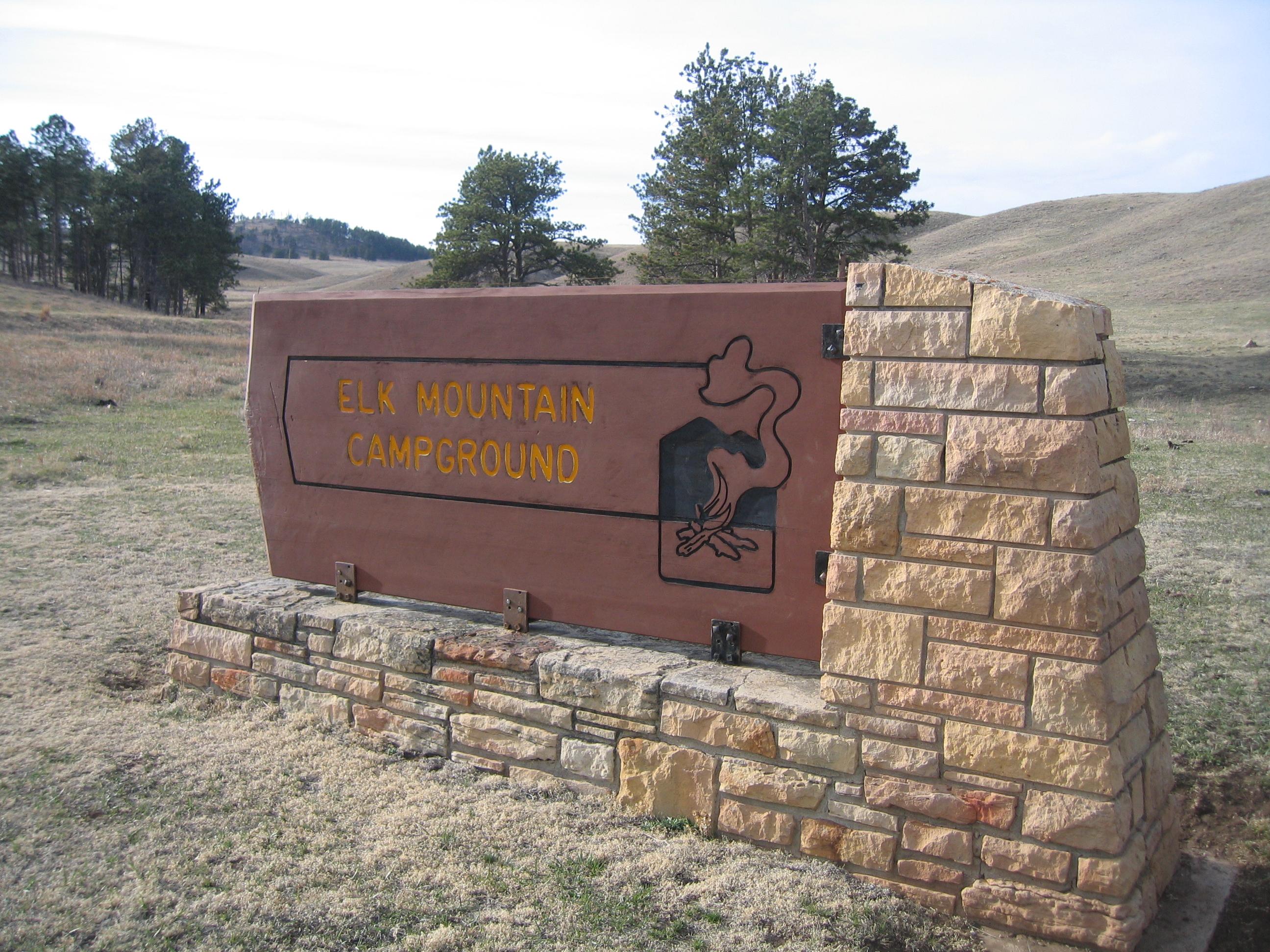 a brown wood and stone sign reading "elk mountain campground"