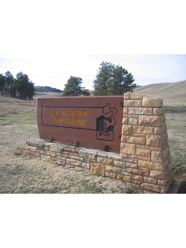 a brown wood and stone sign reading "elk mountain campground"