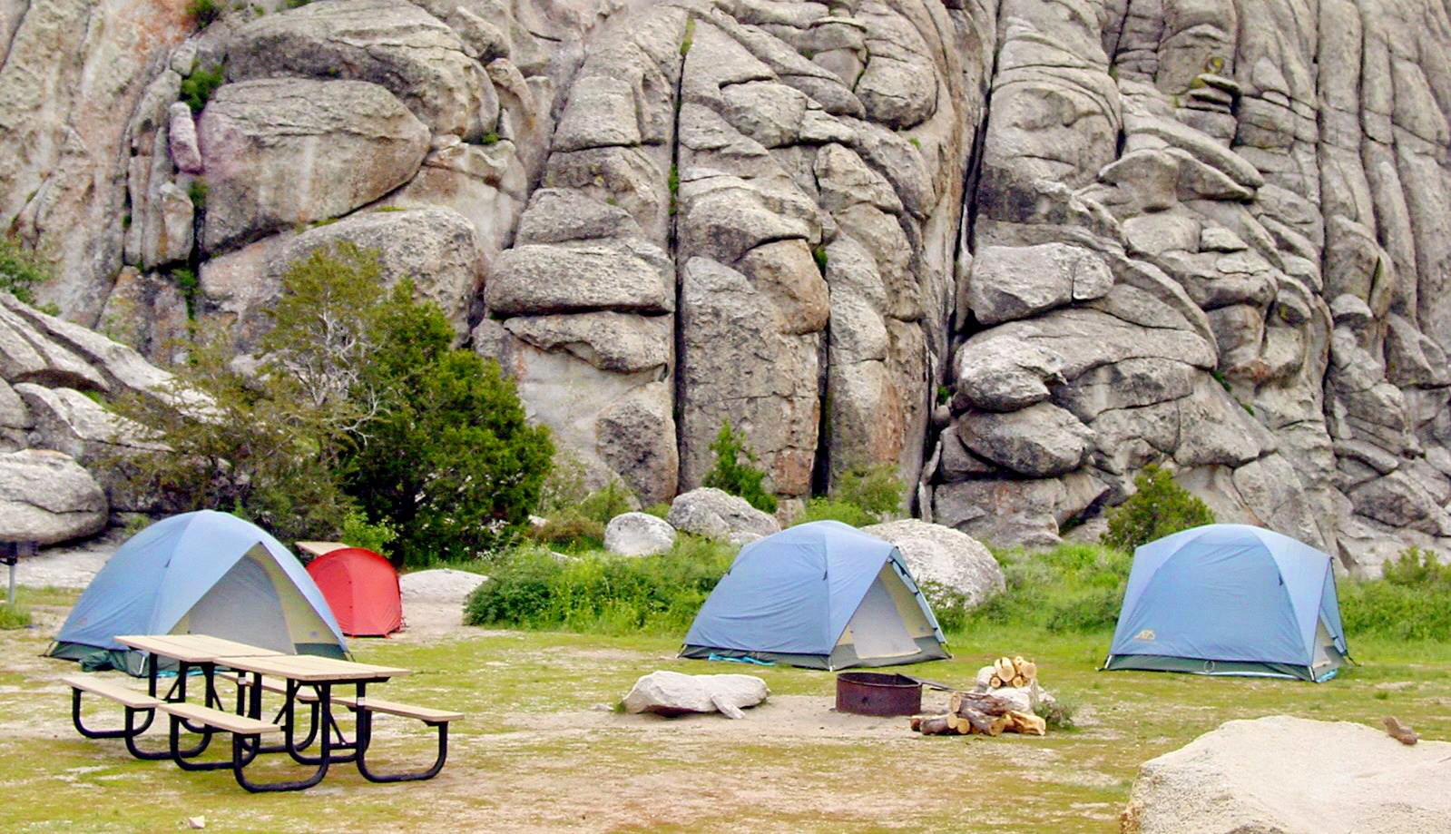 Numerous tents are set up below granite rocks