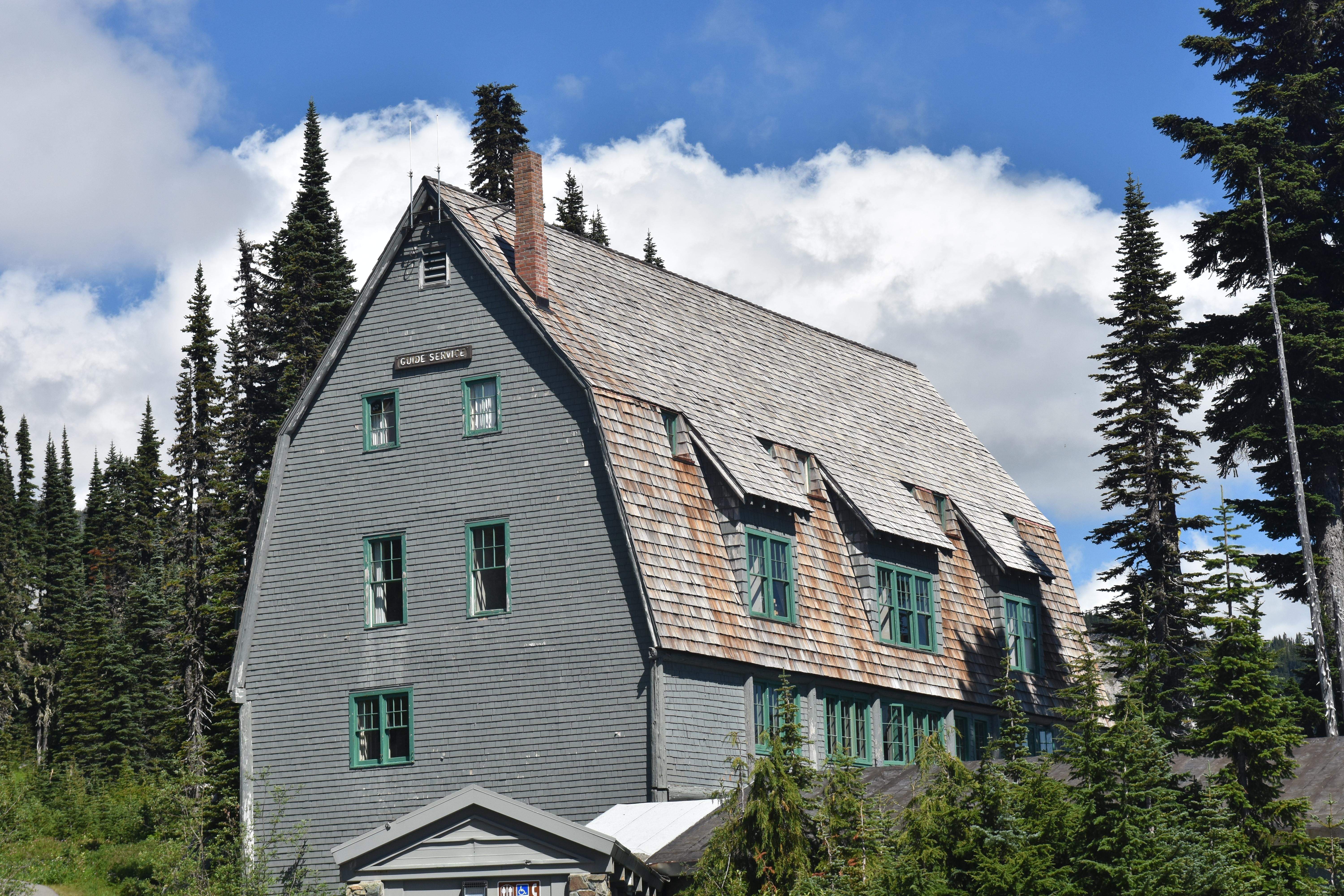A grey building with a sharply-angled roof sits surrounded by trees.