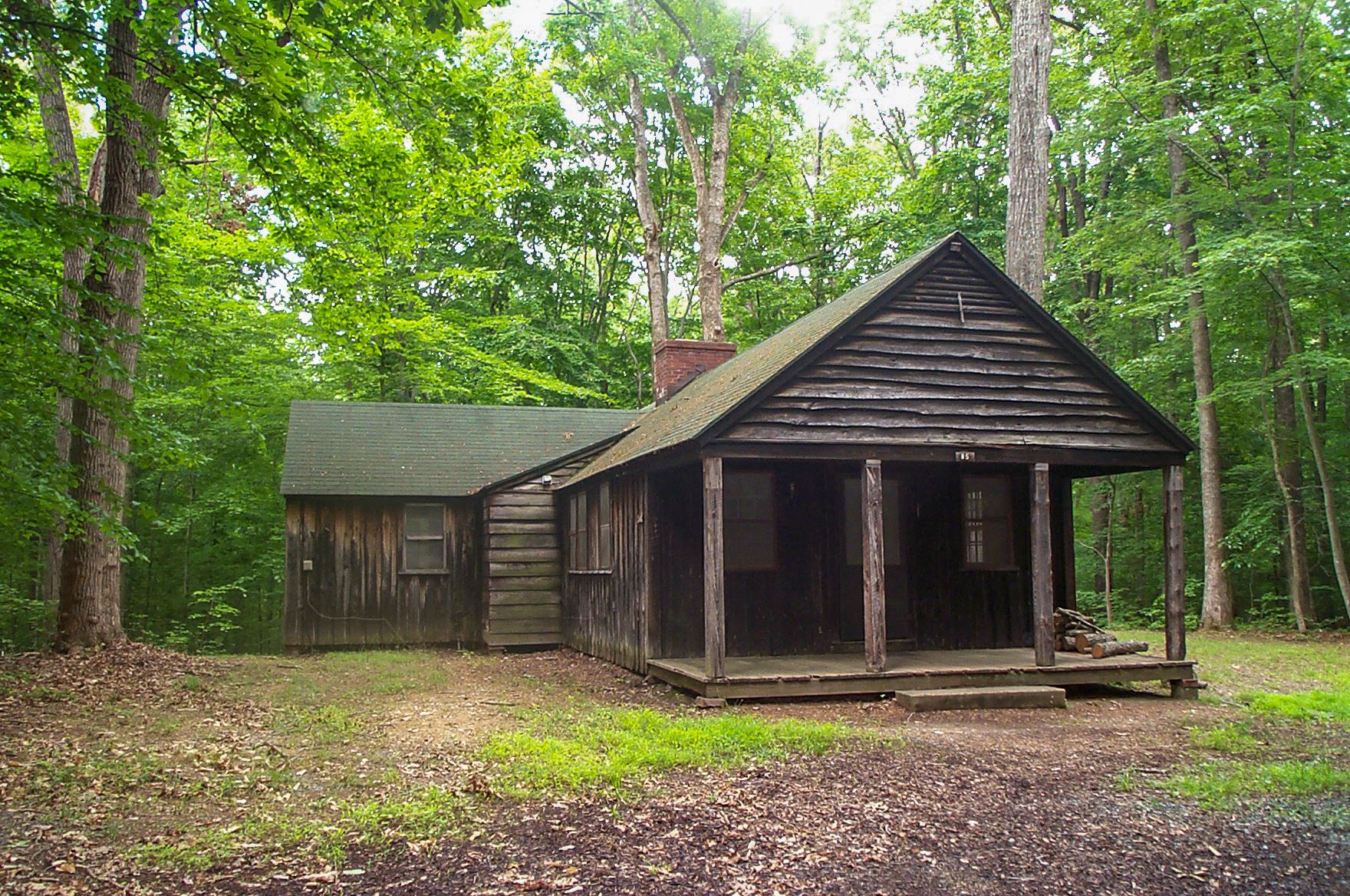 A brown wooden building with a brick fireplace sits among trees