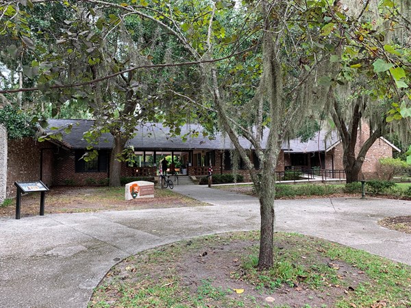 Brick building with wheelchair ramp behind a tree hung with Spanish moss