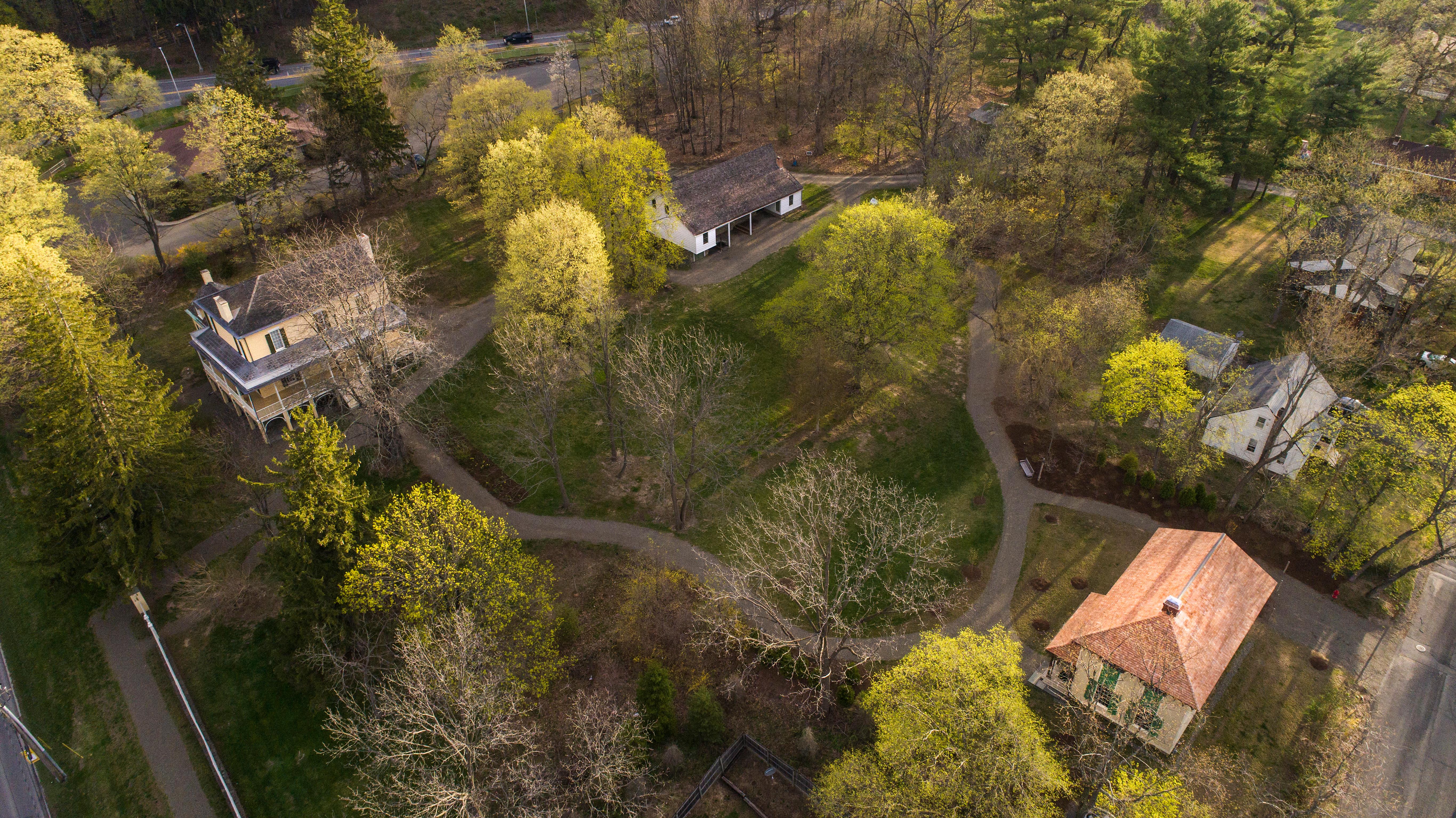 A bird's eye view of several buildings nested among trees and lawn.