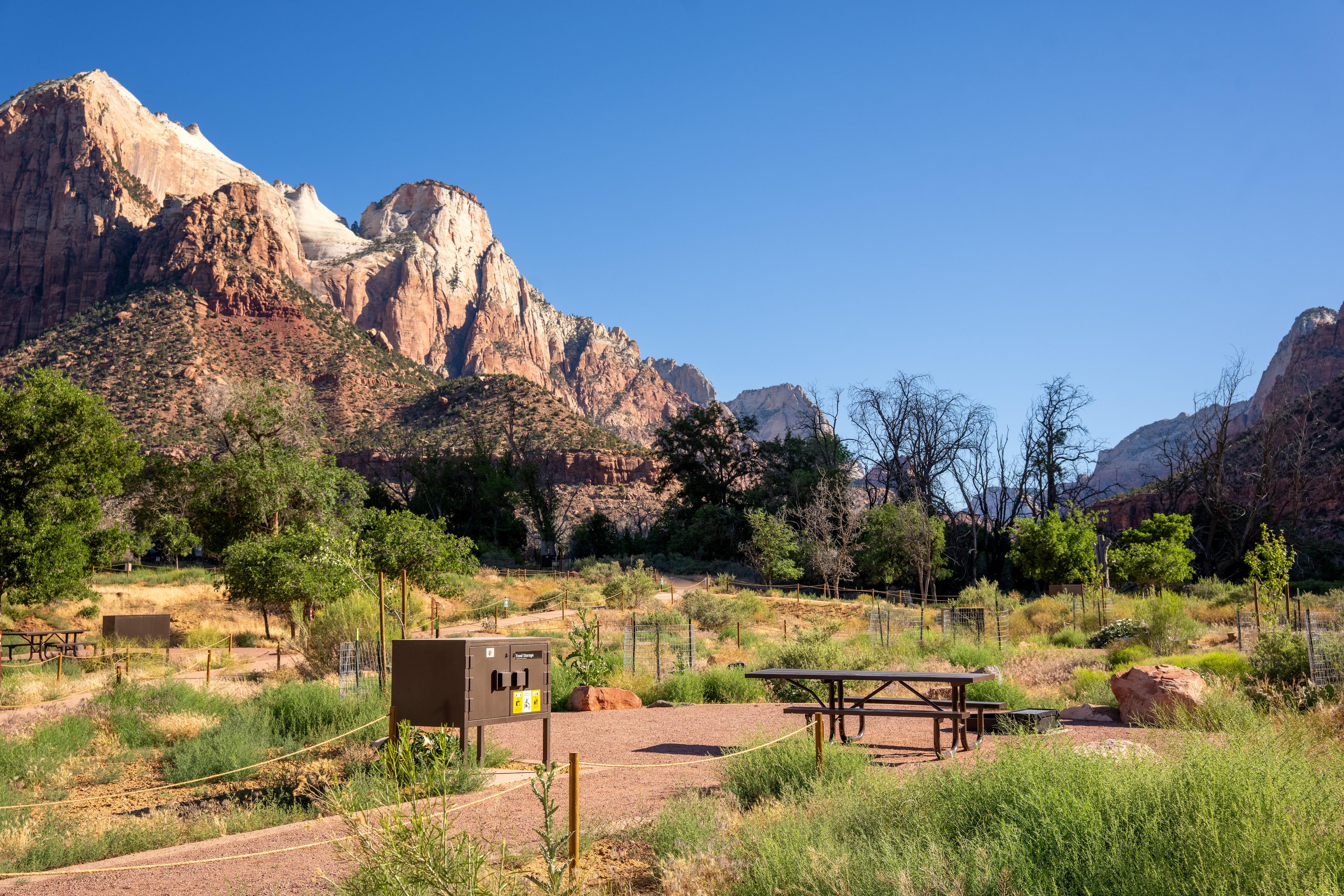 Flat, gravel campsites are spread along a grassy slope with basic amenities.