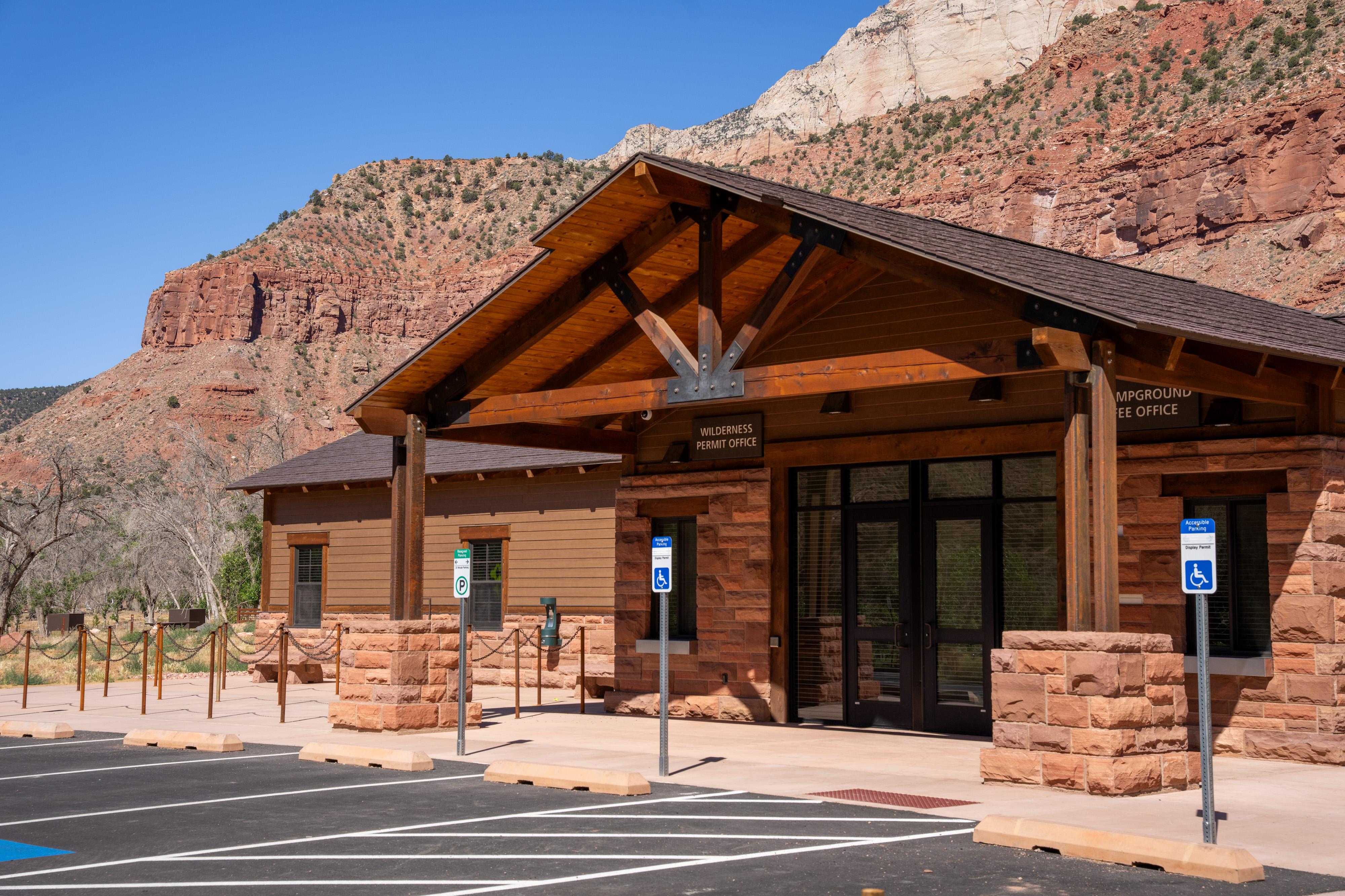 A wood-and-stone building with signs reading "Campground Fee Office" and "Wilderness Permit Office."
