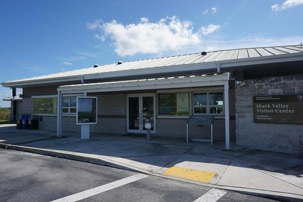 A gray visitor center building under a blue sky with some clouds