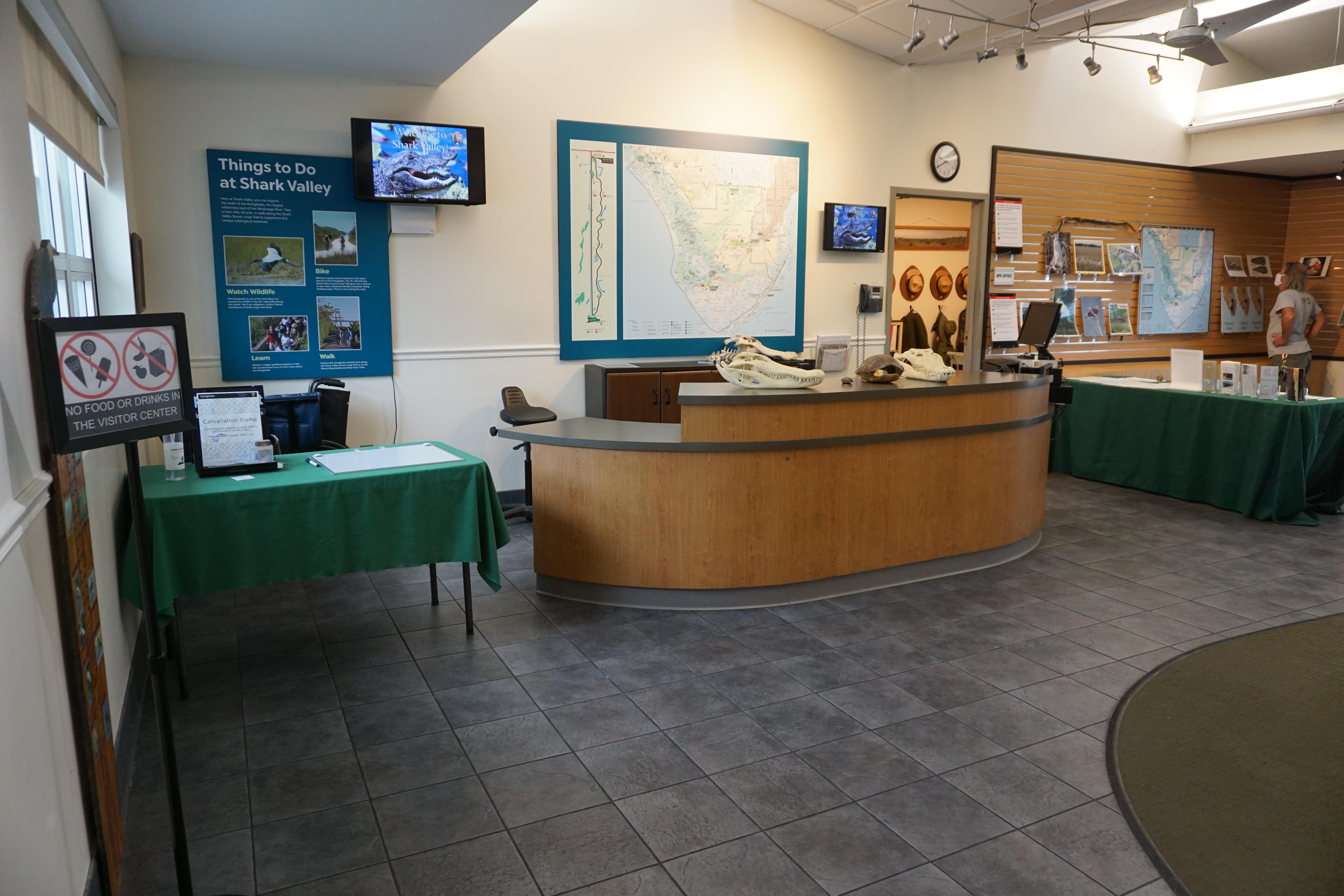 A brown information desk and green display table show a map of the area