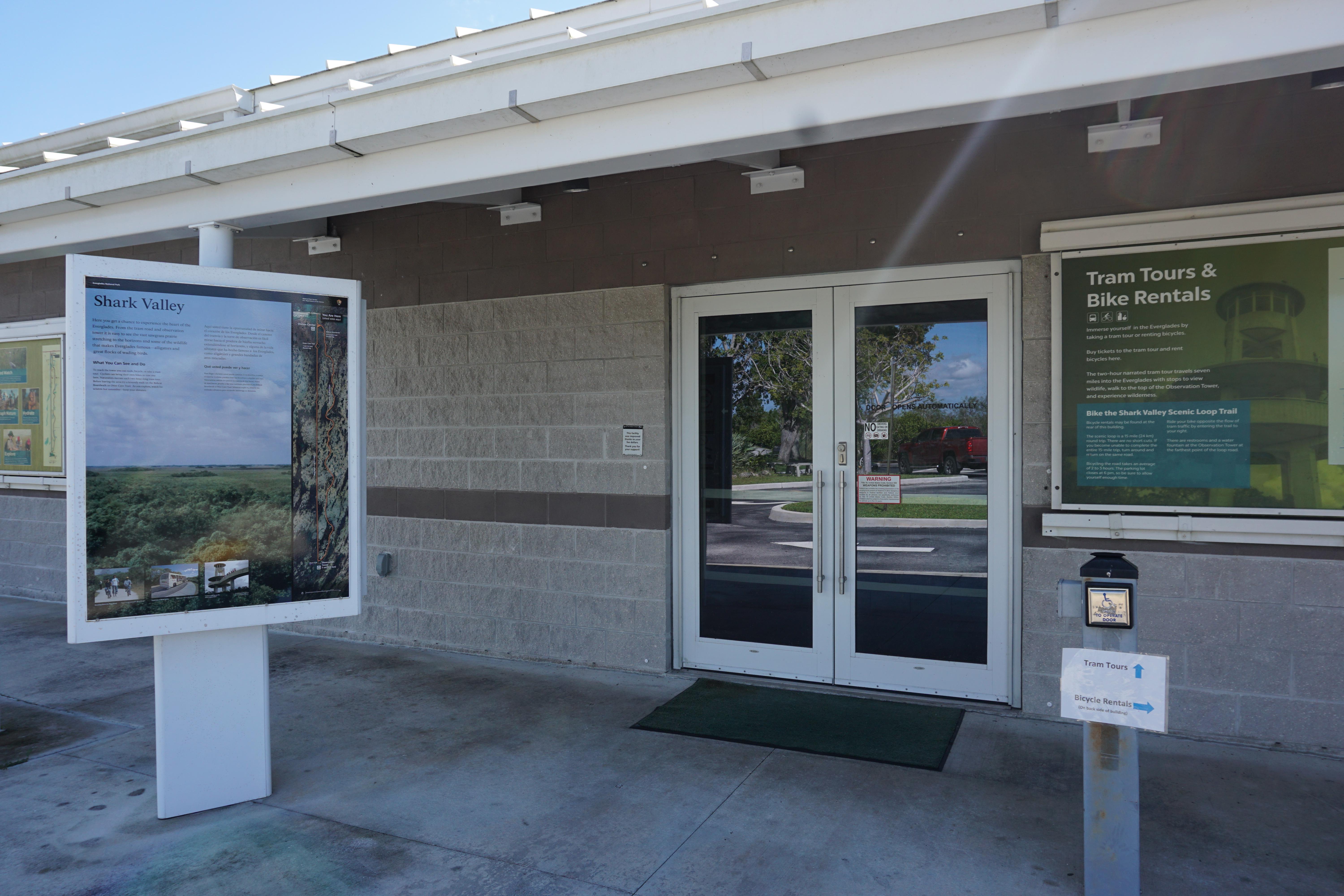 A gray framed glass door and colorful informational poster at the Visitor Center Entrance