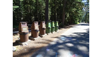 A group of six metal waste bins for trash and recycling.