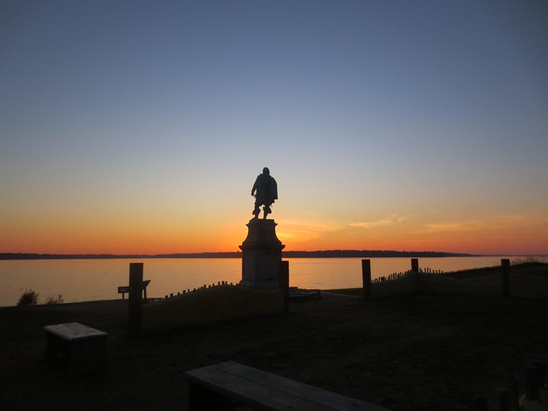 Sunset Over the James River Statue on a pedestal silhouetted against a sunset over a river