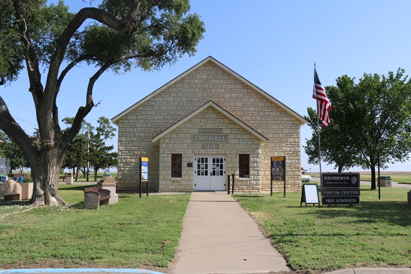 Nicodemus Township Hall A limestone brick building with grass and trees around it