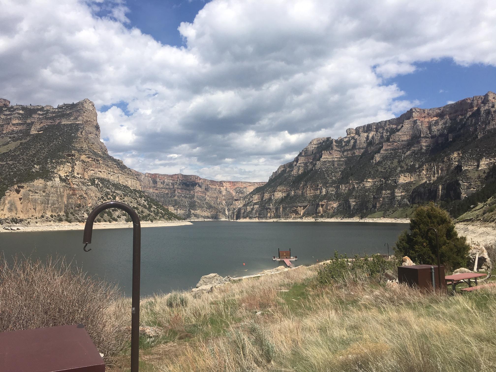 A primitive campground in the foreground with lake and canyon walls in the background.