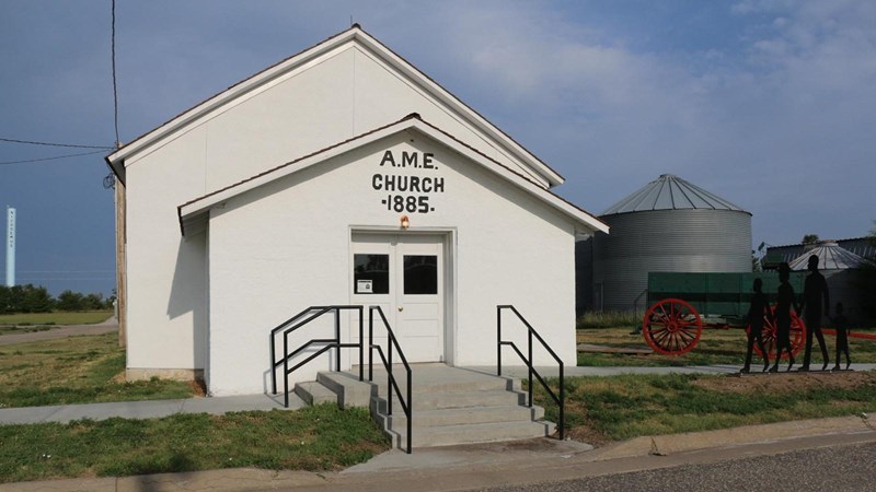 African Methodist Episcopal Church A stucco building painted white with a green wagon out front.