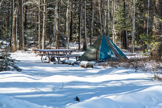 tent and picnic table in snowy forest