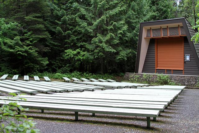 rows of benches before a stone-based stage with wooden backdrop