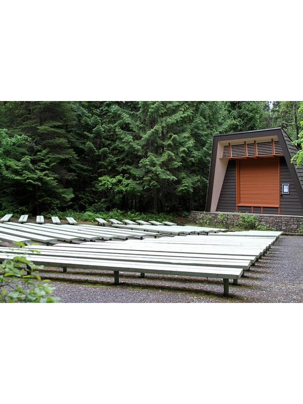 rows of benches before a stone-based stage with wooden backdrop