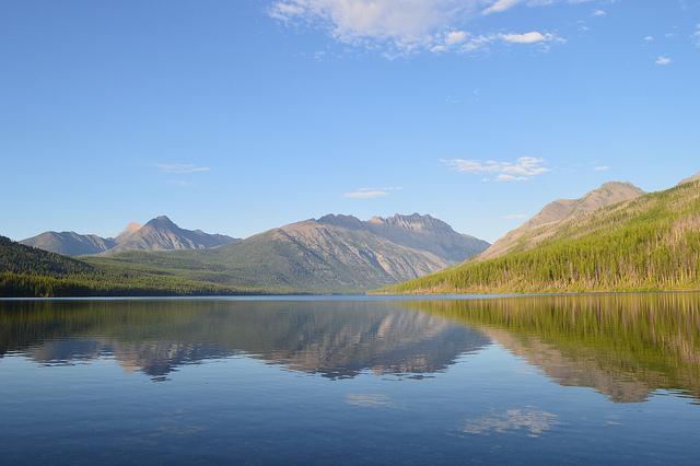 blue sky over mountains, lake, and conifer covered ridge