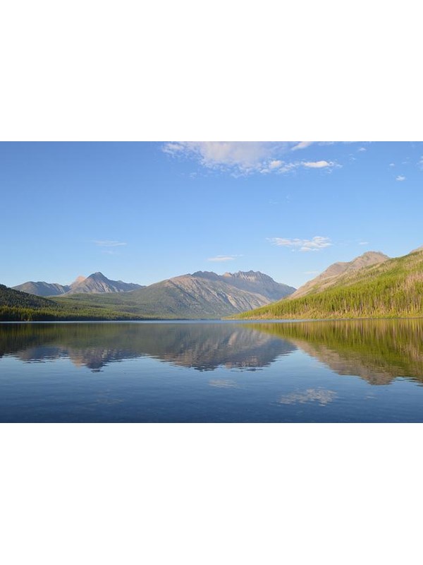 blue sky over mountains, lake, and conifer covered ridge