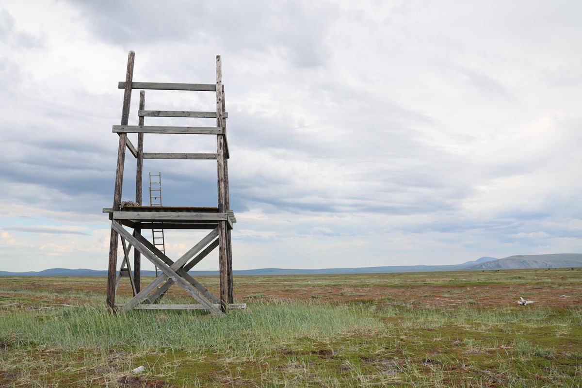 A multistory tower is pictured in the left foreground. Distant beach ridges and hills in the distanc