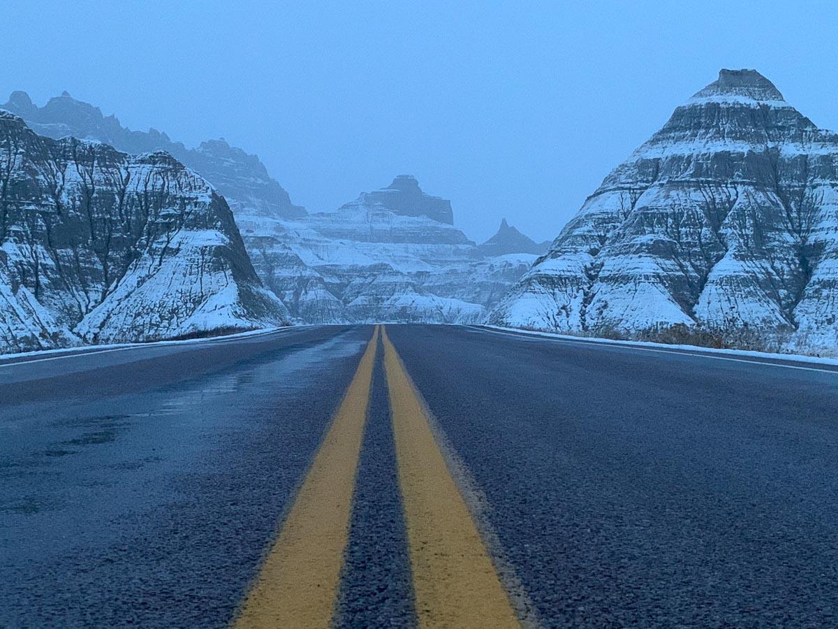 road leading between snow covered badlands formations