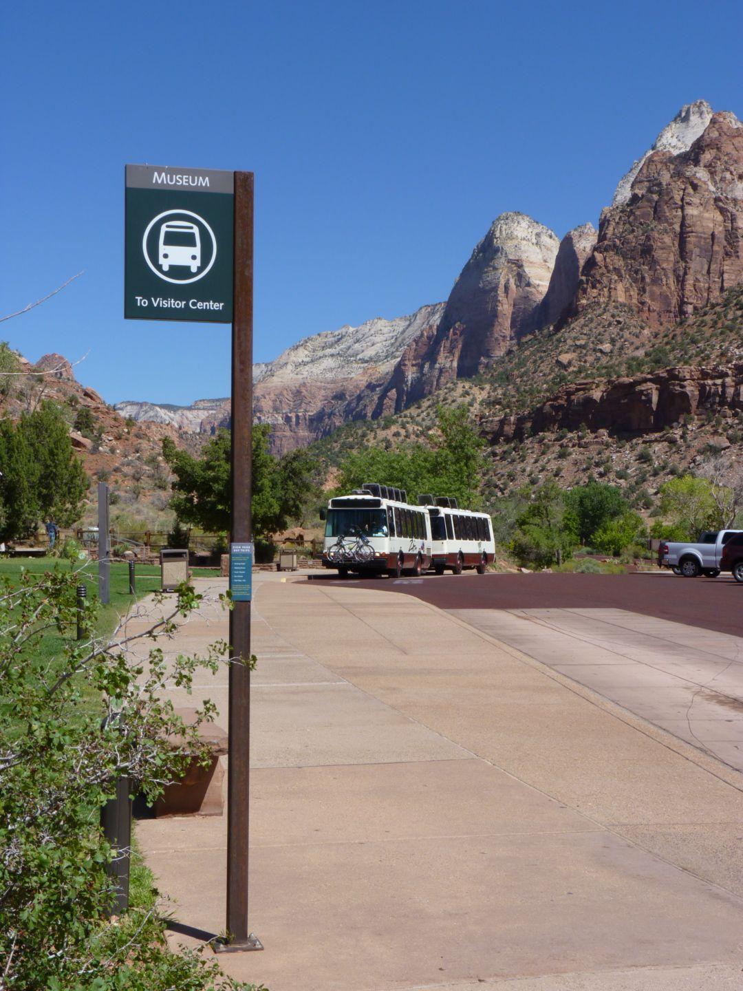 Shuttle Stop sign on a sidewalk with a shuttle bus in the background