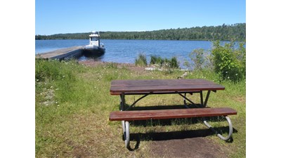 Hay Bay of Lake Superior with a boat at dock and picnic table on the foreground grassy area,