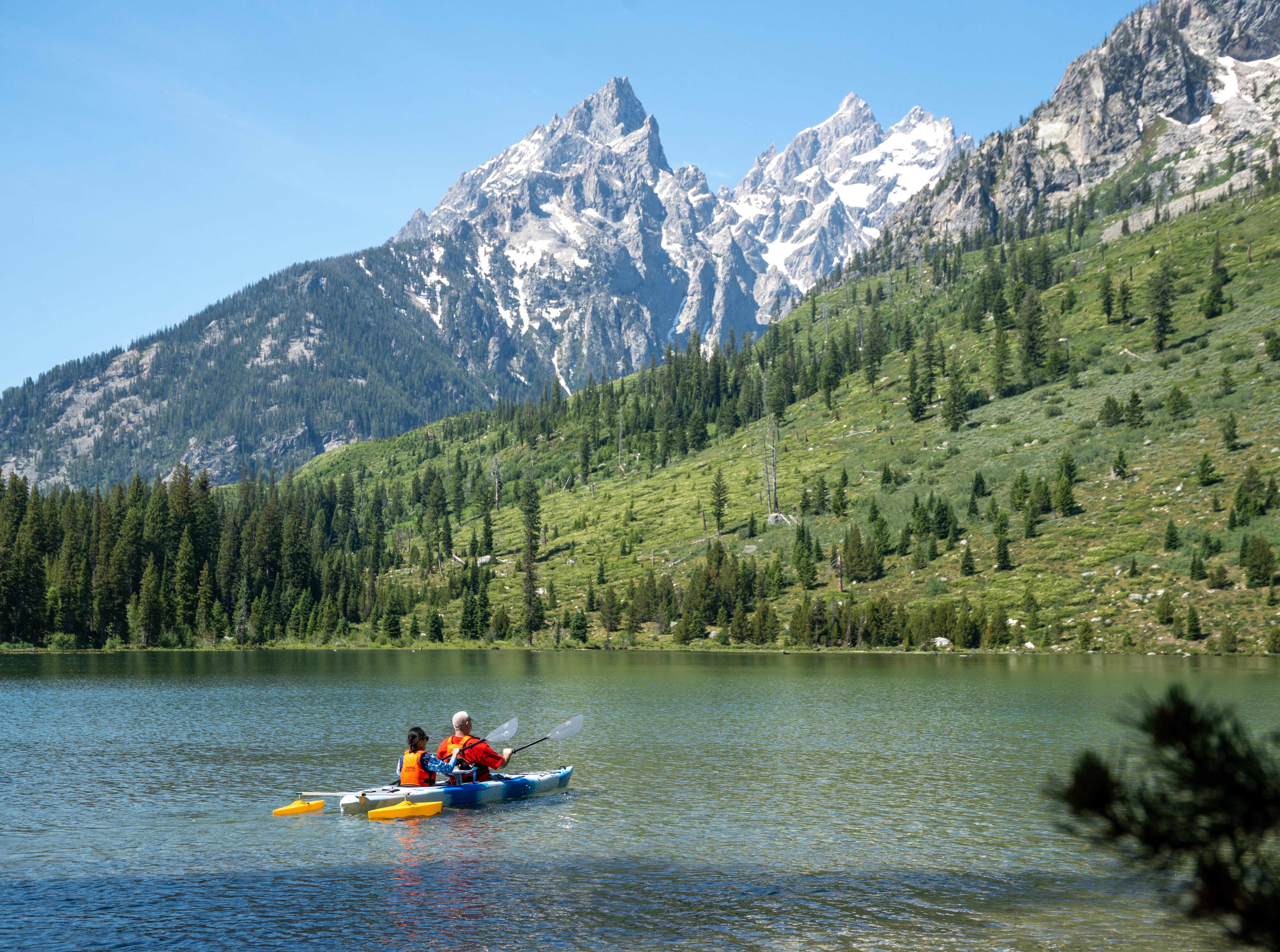 Two kayakers on a lake with a mountain in the background