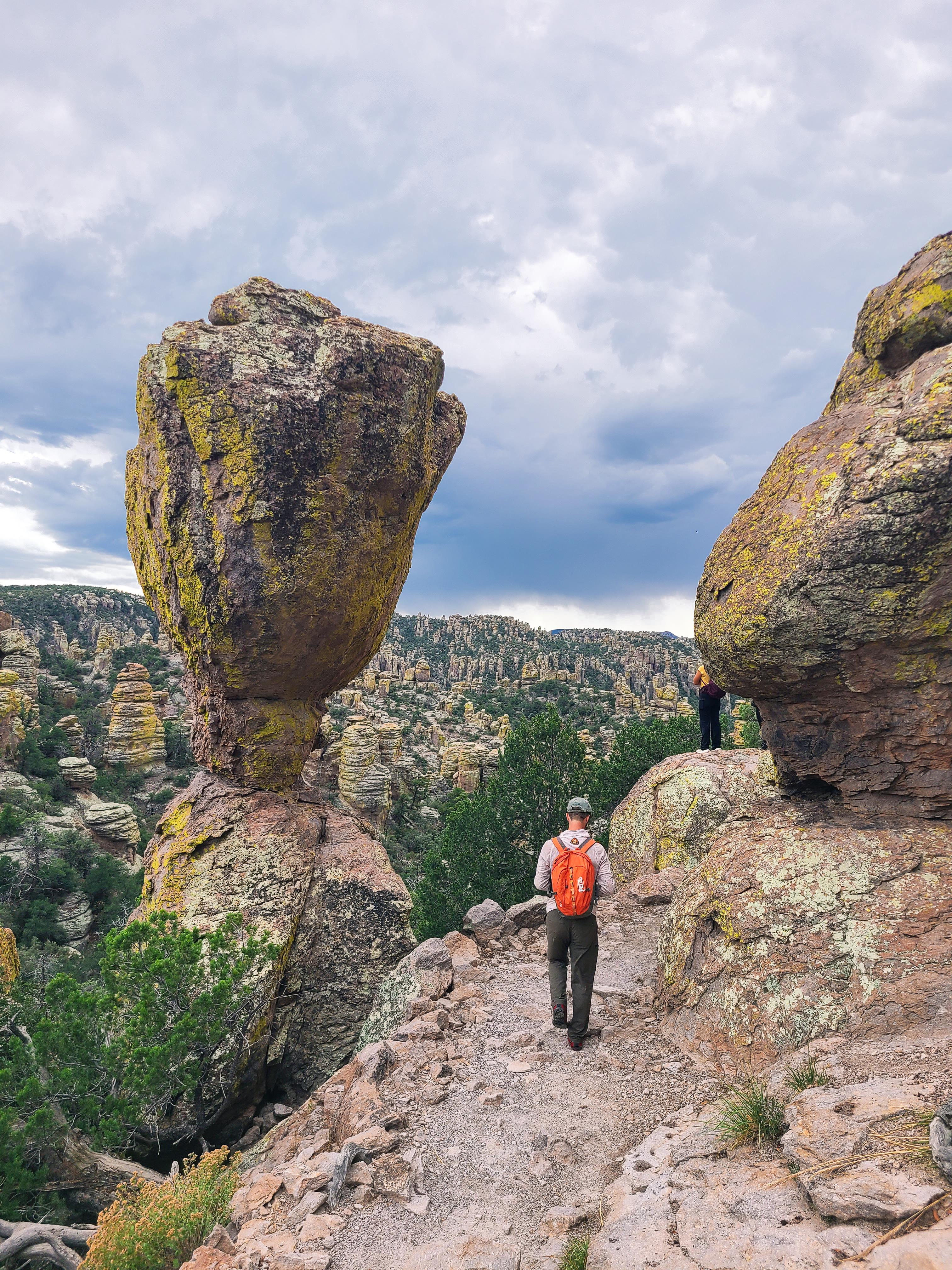 Large rock balanced on a small point with a hiker to the right