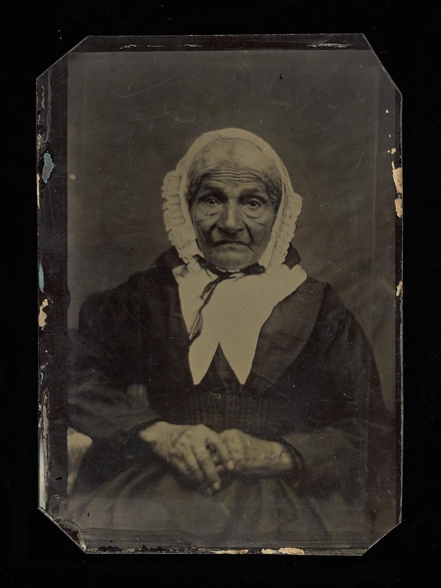 Historic black and white photo of an African American woman seated looking past the camera.