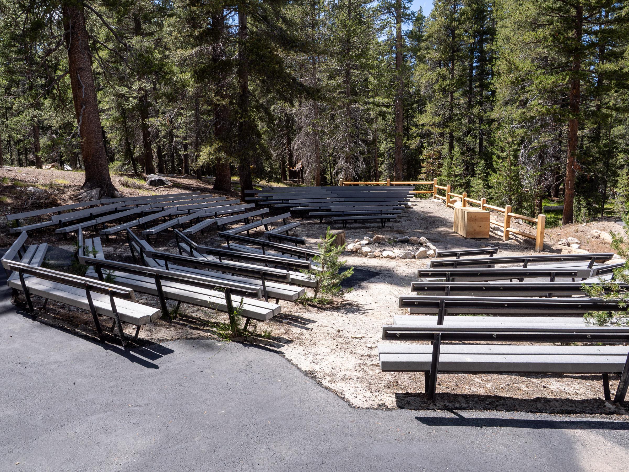 Four rows of raised bleachers surround a fire pit and wooden storage box