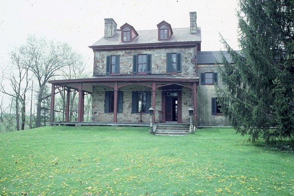 spring green lawn and trees surrounding old stone house